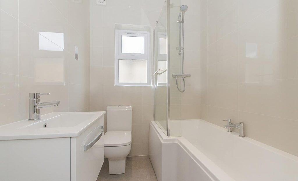 Acton Bright and clean bathroom featuring a bathtub with a glass shower screen, sleek vanity, and natural lighting
