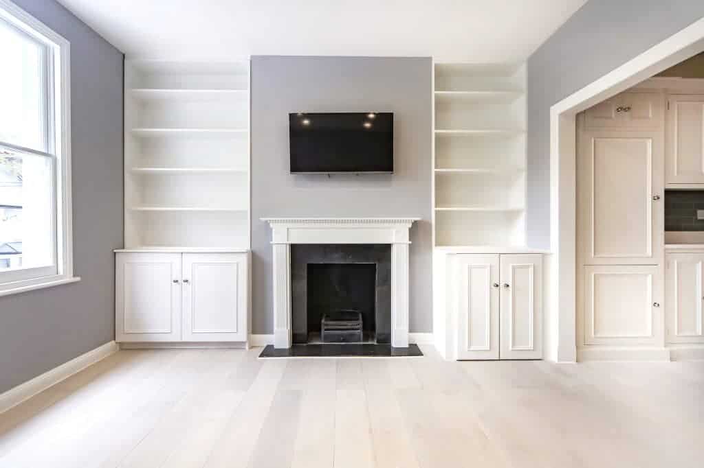 living room with a central fireplace, built-in shelves, and a mounted TV