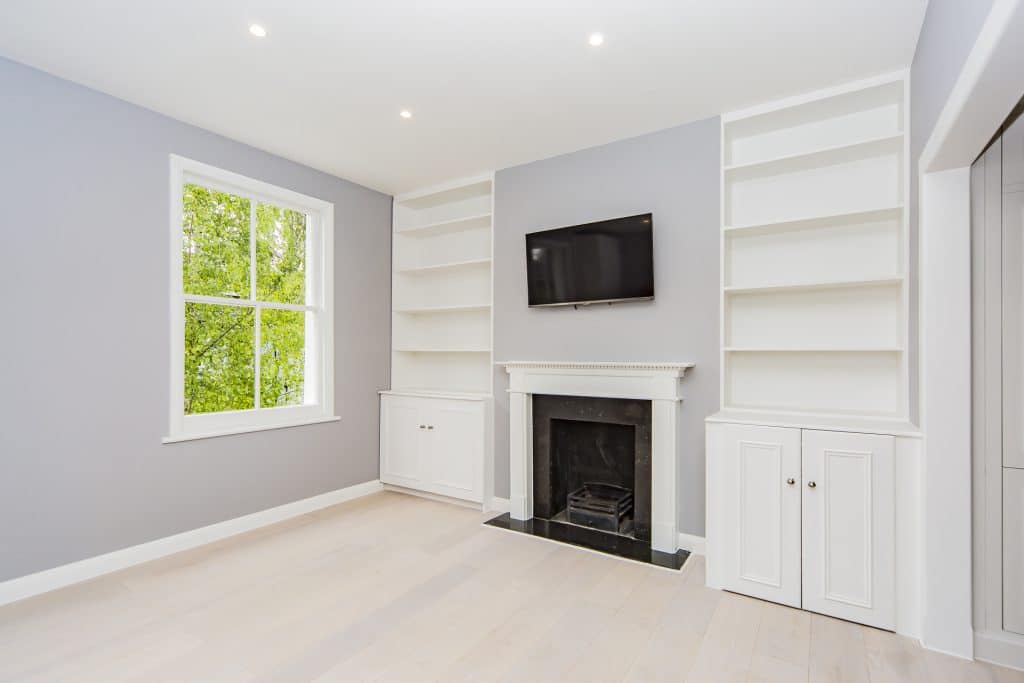 Fulham Bright living room with a fireplace, built-in shelving, and a large window with natural light