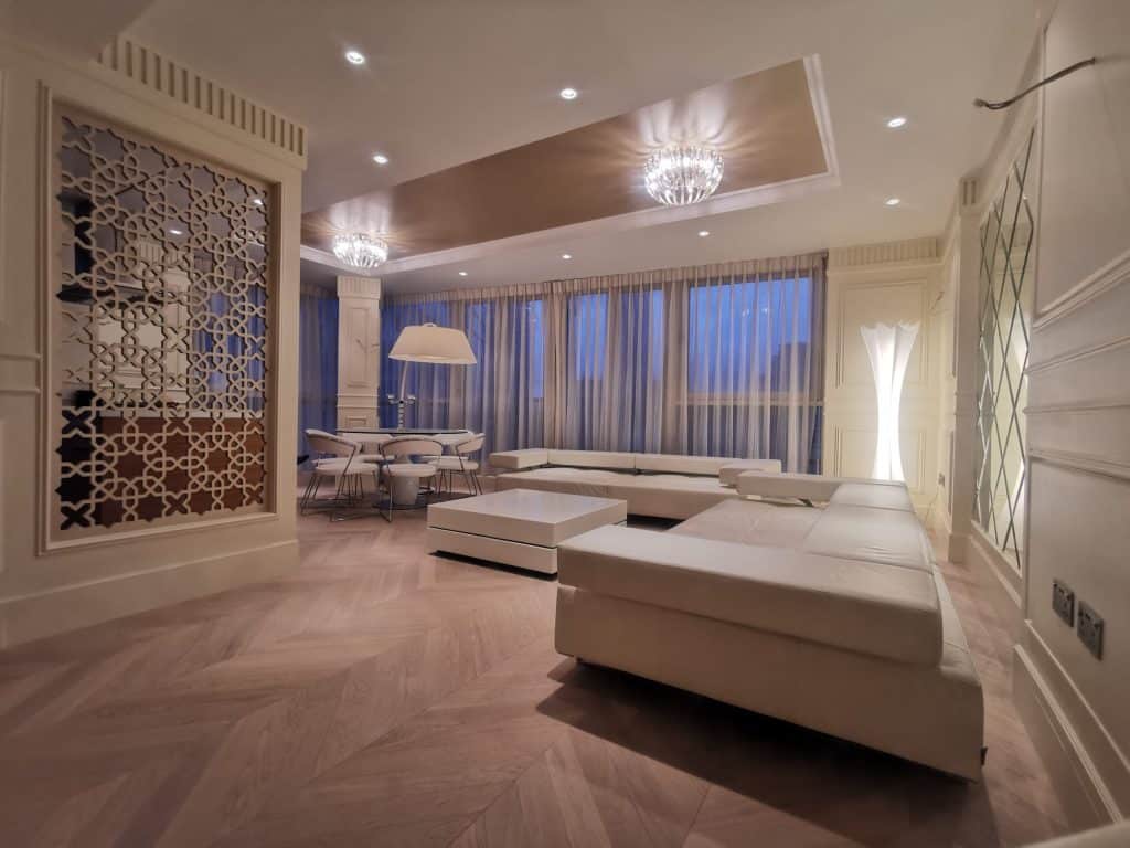 Contemporary living space with warm decor, large windows, and soft furnishings
